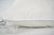 A close-up of the Down Etc. Rhapsody Wrap Down/Feather Pillow, featured at many Hyatt® Hotels, resting on a white bedsheet with soft creases, visible edge stitching, and a small fabric tag along the left seam.