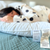 A person in polka dot pajamas sleeps on a bed using the Hollander Holiday Inn® Polyester Pillow | Firm Support. Two tags are visible: one with the product name, the other listing care instructions and materials. The setting feels calm and cozy.